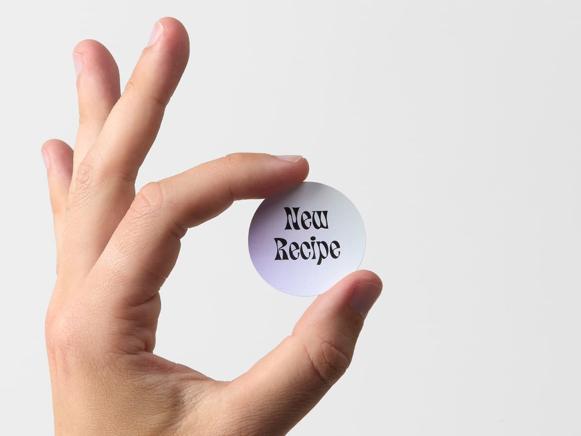 A hand holding a round customized coated sticker.